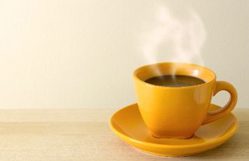  yellow steaming cup of coffee