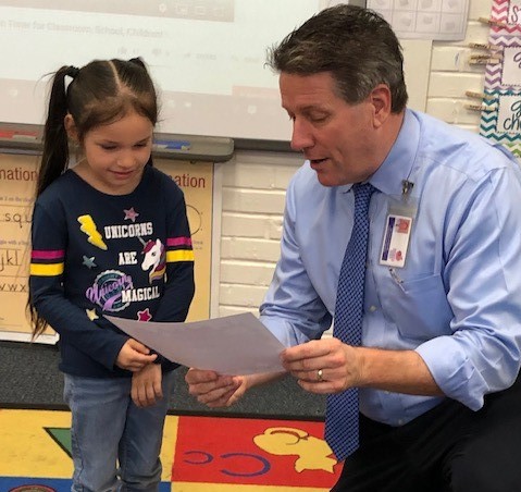 The superintendent reads to a student