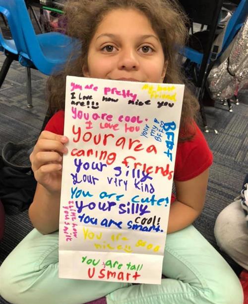a student shows artwork with words of kindness