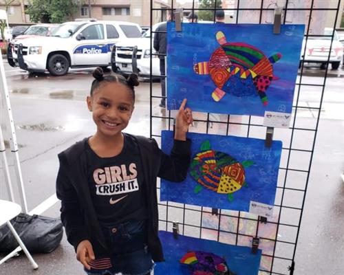 a student proudly shows her artwork
