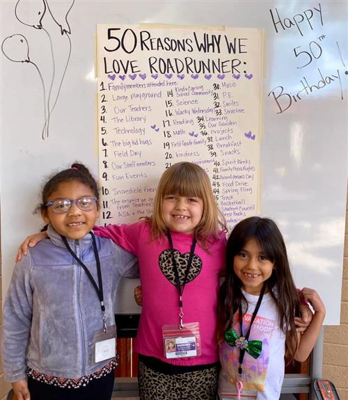 students smile in front of a poster