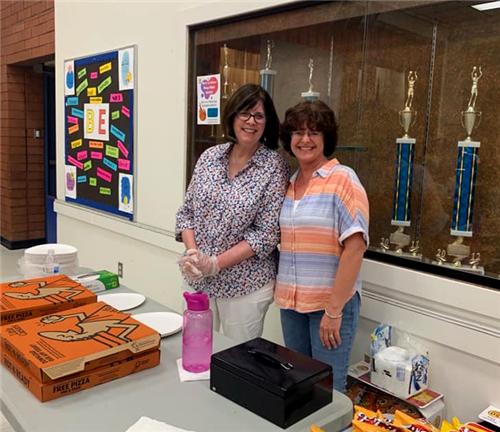 two volunteers hand out pizza